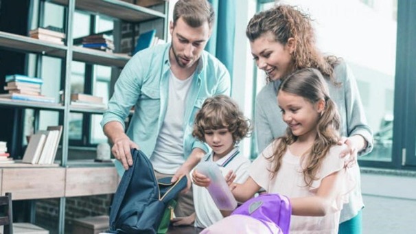 Pais ajudando o filho a organizar os materiais escolares para retomar a rotina escolar após as férias com tranquilidade e motivação